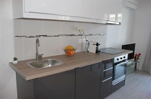 Modern kitchen with a stainless steel sink, oven, and gas stove, complete with a small potted plant and a vase with a single flower.