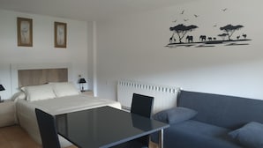 Ein modernes Hotelzimmer mit Bett, Esstisch, Sofa und Wanddeko mit Tiermotiven.