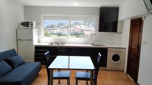 Eine kleine Küche mit Fenster, einer Waschmaschine, einer Mikrowelle und einem Sofa.