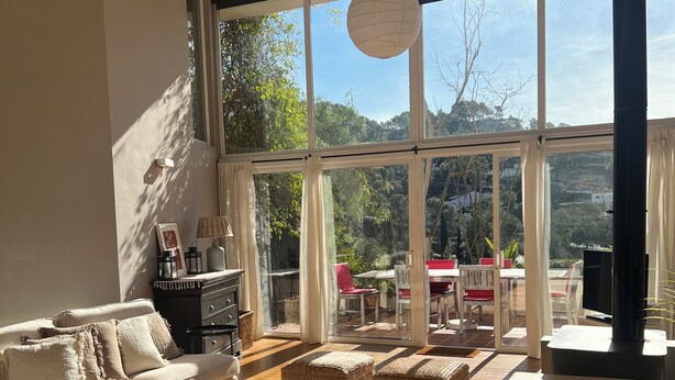 A spacious living room with a large window, a sofa, a coffee table, and a fireplace.