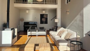 A spacious living area with a piano, sofa, and a balcony with a railing.