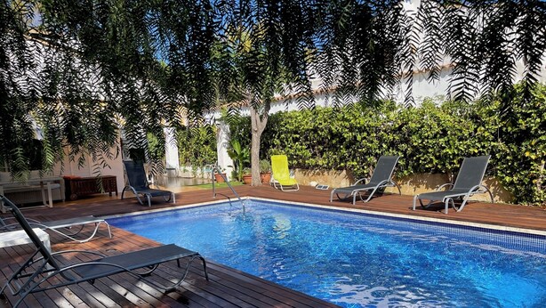 En swimmingpool med ett trädäck och solstolar.