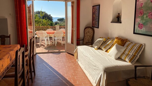 Ein gemütliches Zimmer mit einem Bett, einem Esstisch mit Stühlen und Blick ins Freie.