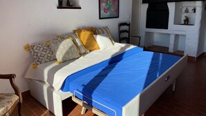 Ein Schlafzimmer mit Bett, Sessel, Kamin und einem Regal mit Figuren.