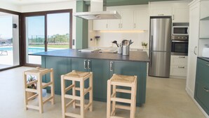 A modern kitchen with a large island, built-in appliances, and a view of a swimming pool. - Ferrer de Shorta Modern holiday home for 10, private pool, A/C and Wi-Fi (S'Horta)