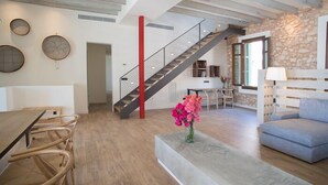 A spacious living area with a staircase, a dining table with chairs, a sofa, and a vase of flowers. - Ferrer de Shorta Modern holiday home for 10, private pool, A/C and Wi-Fi (S'Horta)