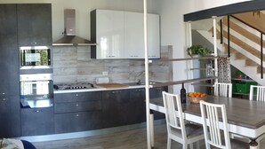 Una cucina moderna con mobili scuri, forno integrato e un'area pranzo con tavolo e sedie.