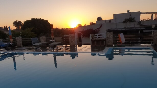 Una piscina con sedie a sdraio e un tramonto sullo sfondo.