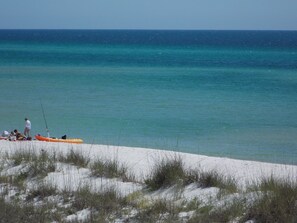 Una playa con agua turquesa cristalina, una orilla arenosa y algunas personas y un kayak.