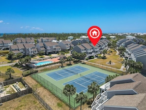 Un quartier résidentiel comprenant plusieurs maisons à deux étages, un court de tennis et une piscine.