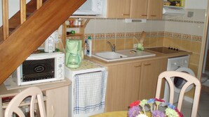 Een kleine keuken met een magnetron, koffiezetapparaat, spoelbak en houten kastjes.