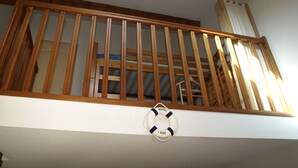 Een houten balkon met een reddingsboei aan de muur.