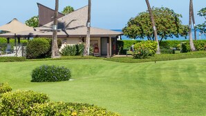 Propiedad frente a la playa con una casa, palmeras y un césped bien cuidado.