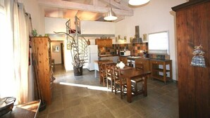 A spacious kitchen with wooden cabinets, a dining area with a table and chairs, and a staircase leading to an upper level.