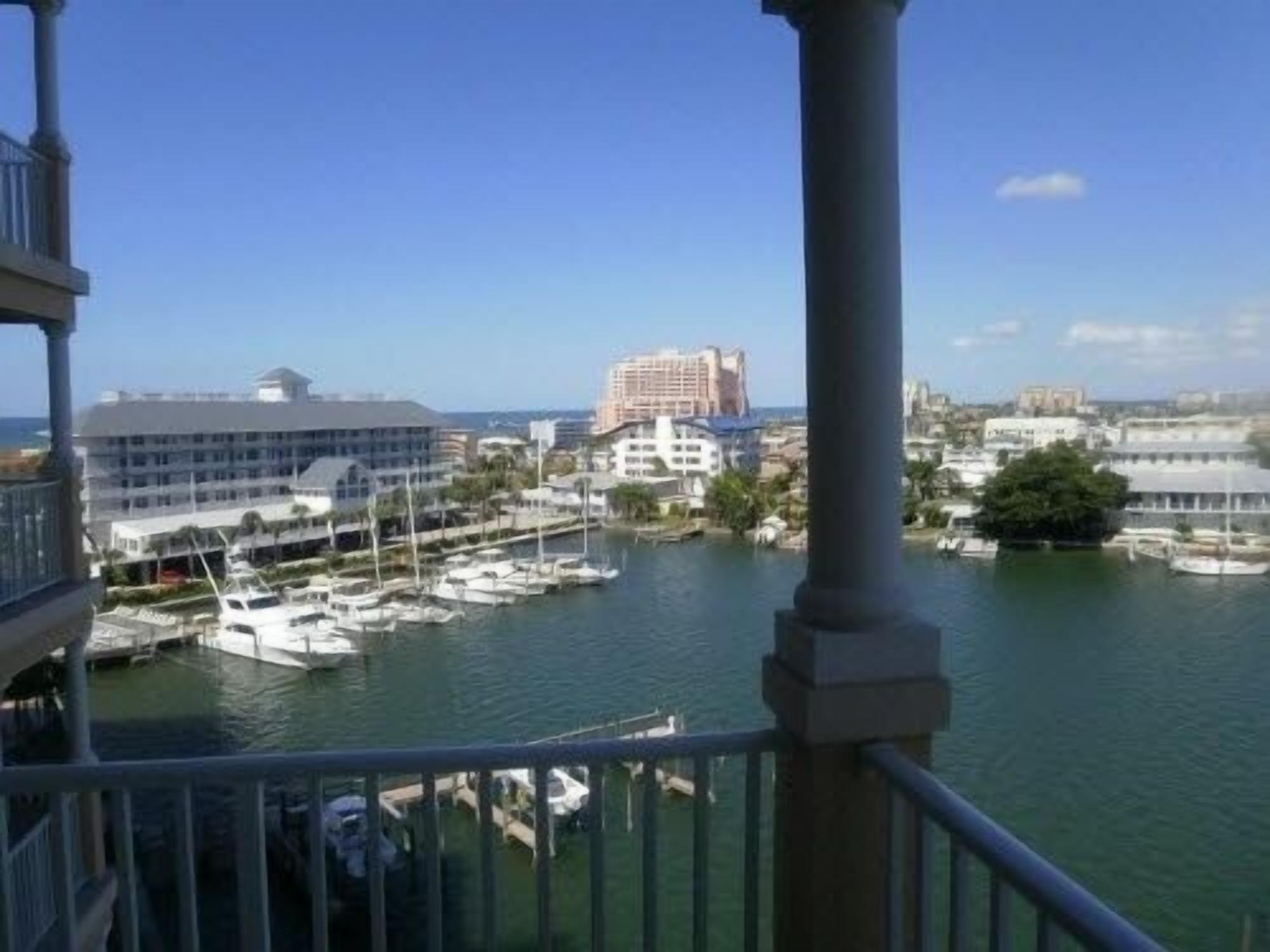A marina with boats docked, a large building in the background, and a clear blue sky.