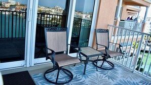 Un balcon avec deux chaises et une table, offrant une vue sur un port de plaisance et le paysage urbain.