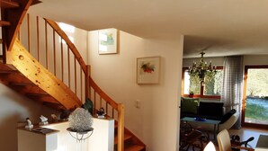 A wooden staircase leading to a living area with a dining table, chairs, and a sofa. - House right on the edge of the forest, right at the foot of the Black Forest  (Schopfeim Ortsteil Enkenstein)