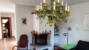 A living room with a fireplace, a rocking chair, a blue table with a remote control, and a black sofa. - House right on the edge of the forest, right at the foot of the Black Forest  (Schopfeim Ortsteil Enkenstein)