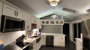 A modern kitchen with white cabinetry, stainless steel appliances, and a central island. - Relax in your home; yards from the Frankfort Beach and the downtown attractions. (Frankfort)