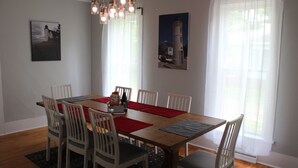A dining area with a wooden table, white chairs, red placemats, and a hanging light fixture. - Relax in your home; yards from the Frankfort Beach and the downtown attractions. (Frankfort)