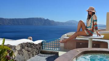 A person sitting by a pool with a view of the sea and mountains.