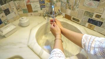 Un baño con lavamanos, grifo y dispensador de jabón.