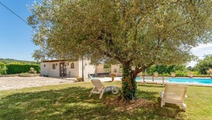 Eine Villa mit Swimmingpool, zwei Liegestühlen und einem Baum im Garten.