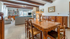 Un coin repas avec une table et des chaises en bois, un canapé, une cheminée et une bibliothèque.