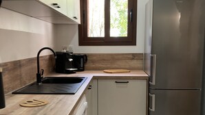 A compact kitchen with a stainless steel refrigerator, a coffee maker, and a window with a view of greenery. - VILLA en Pierre 4 persons near PORTO-VECCHIO HEATED SWIMMING POOL  (Lecci)