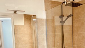 A modern bathroom with a glass-enclosed shower, a white vanity with a black faucet, and a round mirror. - VILLA en Pierre 4 persons near PORTO-VECCHIO HEATED SWIMMING POOL  (Lecci)
