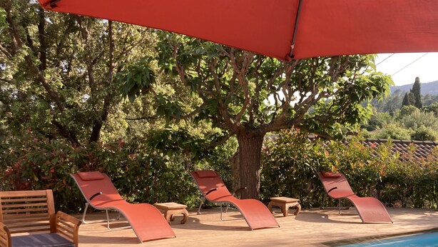 A wooden deck with lounge chairs and a table, a swimming pool, and a large tree providing shade. - VILLA en Pierre 4 persons near PORTO-VECCHIO HEATED SWIMMING POOL  (Lecci)