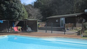 A swimming pool with a wooden deck, a covered seating area, and a small building with a door. - Conditioned cottage at the foot of Albéres with pool prox. Sea (Argelès-Sur-Mer)