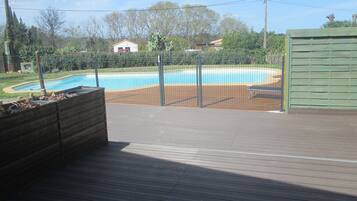 A wooden deck with a pool in the background.
