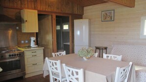 A wooden interior with a dining table, chairs, a stove, and a refrigerator. - Conditioned cottage at the foot of Albéres with pool prox. Sea (Argelès-Sur-Mer)