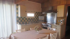 A compact kitchen with wooden cabinets, a stove, a microwave, and a sink. - Conditioned cottage at the foot of Albéres with pool prox. Sea (Argelès-Sur-Mer)