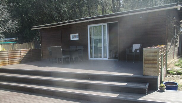 A wooden deck with steps leading to a covered patio area with a table and chairs. - Conditioned cottage at the foot of Albéres with pool prox. Sea (Argelès-Sur-Mer)