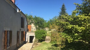 Une cour intérieure avec un bâtiment d’un côté, un petit arbre et un ciel bleu dégagé.