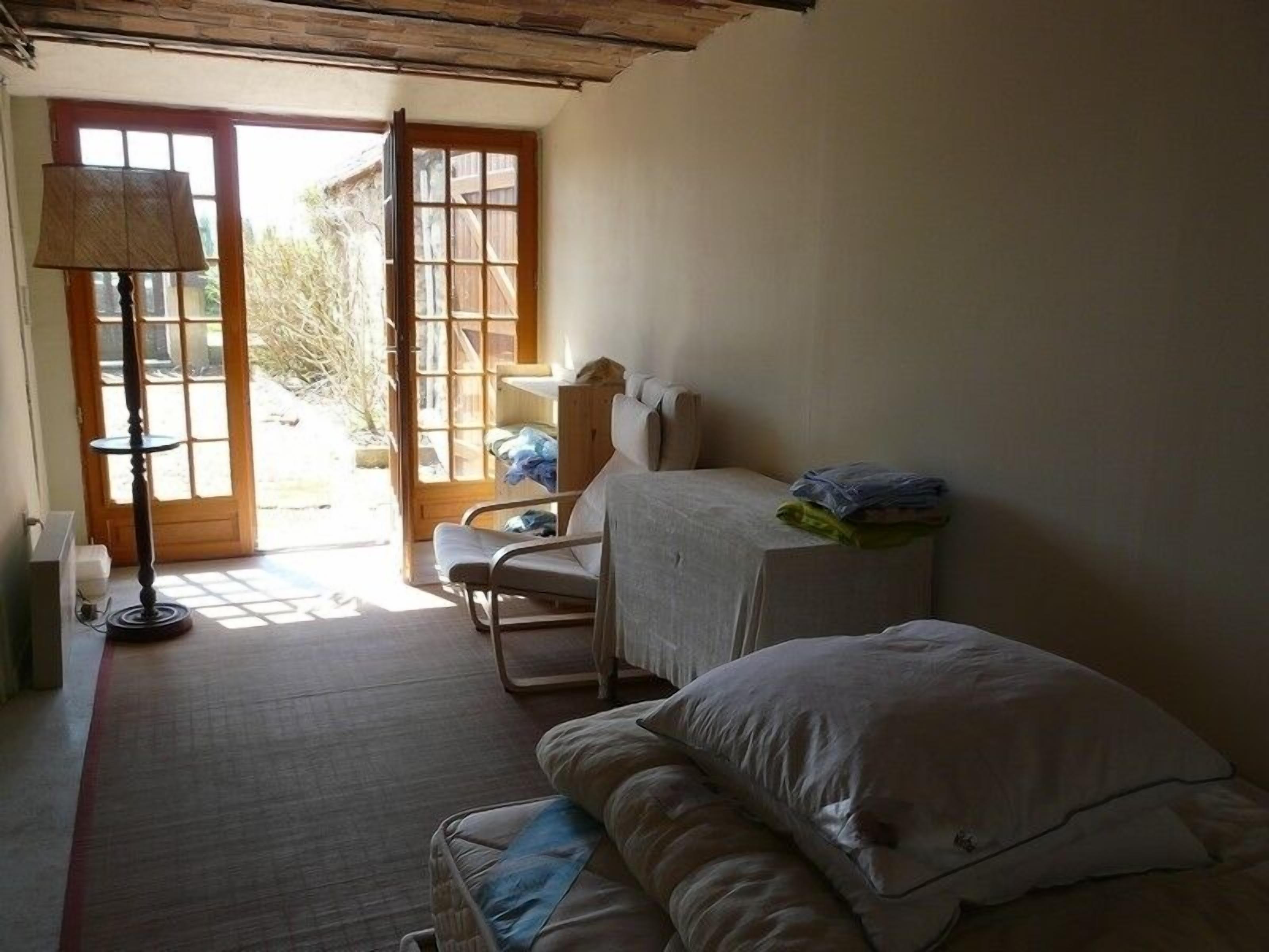 Een kleine, gezellige kamer met een bed, een stoel en een tafel. Er is een raam met uitzicht op buiten.