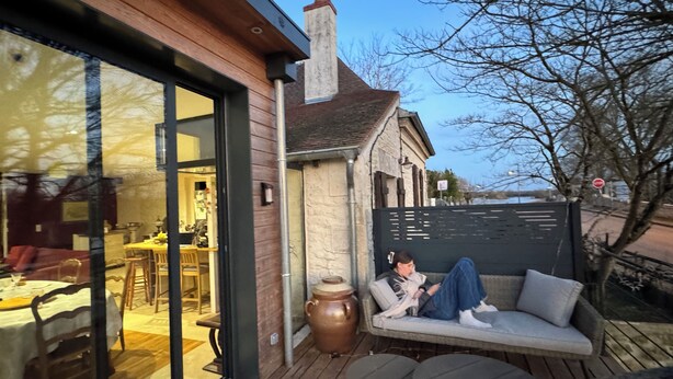 Un espace extérieur accueillant, aménagé avec une table et des chaises, un grand vase et offrant une vue sur le paysage environnant.