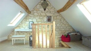 Une chambre à coucher de style loft avec un mur en pierre, une porte en bois, un bureau, un banc et une vue sur le ciel.