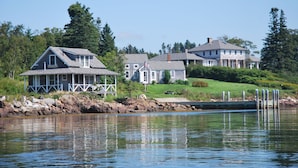 Une propriété située au bord de l’eau, comprenant plusieurs maisons, un quai et une zone herbeuse.