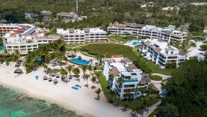 An aerial view of a resort with multiple buildings, a central pool, and a beach.