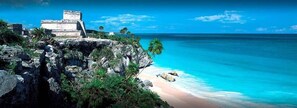 A coastal scene with a clear view of a beach and a stone structure.