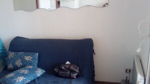 A room with a blue sofa, a wooden table, and a wall-mounted mirror.