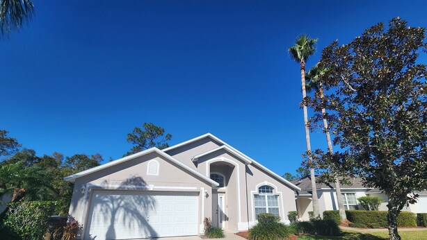 A single-story house with a garage, a small porch, and a well-maintained lawn. - LAKE BERKLEY-(1059LB) - 4BR 3BA Pool Home, 2 Master Suites, gated Resort (Kissimmee)