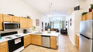 A modern kitchen with wooden cabinets, stainless steel appliances, and a central island. - LAKE BERKLEY-(1059LB) - 4BR 3BA Pool Home, 2 Master Suites, gated Resort (Kissimmee)