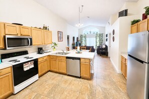 A modern kitchen with wooden cabinets, stainless steel appliances, and a central island. - LAKE BERKLEY-(1059LB) - 4BR 3BA Pool Home, 2 Master Suites, gated Resort (Kissimmee)