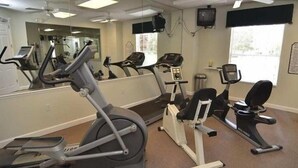 A gym with cardio machines, a mirror, and a window. - LAKE BERKLEY-(1059LB) - 4BR 3BA Pool Home, 2 Master Suites, gated Resort (Kissimmee)
