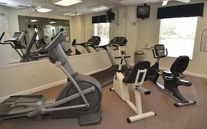 A gym with cardio machines, a mirror, and a window.
