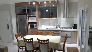 Cocina compacta con comedor, que incluye refrigerador, microondas, estufa y sillas de madera.